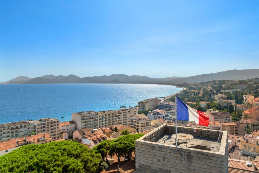 Panoramic view of Cannes coastline with French flag, best places to visit in france